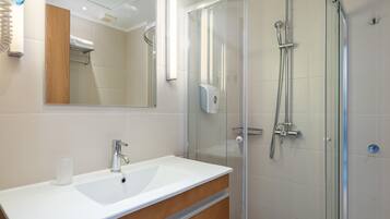 Une salle de bain moderne avec une douche à parois de verre, un lavabo blanc et un meuble-lavabo en bois.