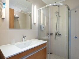 Une salle de bain moderne avec une douche à parois de verre, un lavabo blanc et un meuble-lavabo en bois.