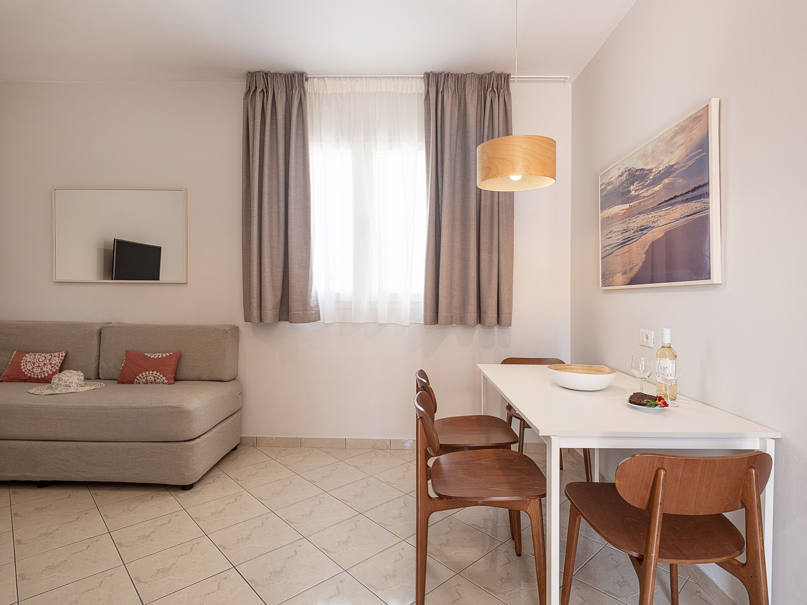 A modern living room with a sofa, dining table, chairs, and a painting on the wall.