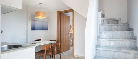 Una cocina moderna con comedor, una escalera y vistas al exterior.