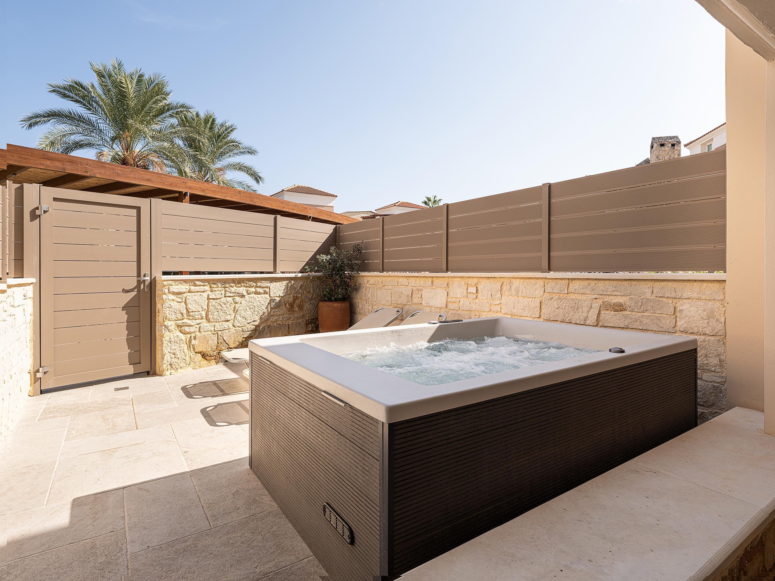 Ein Wellnessbereich mit Whirlpool, Steinwänden und einer Holzpergola.