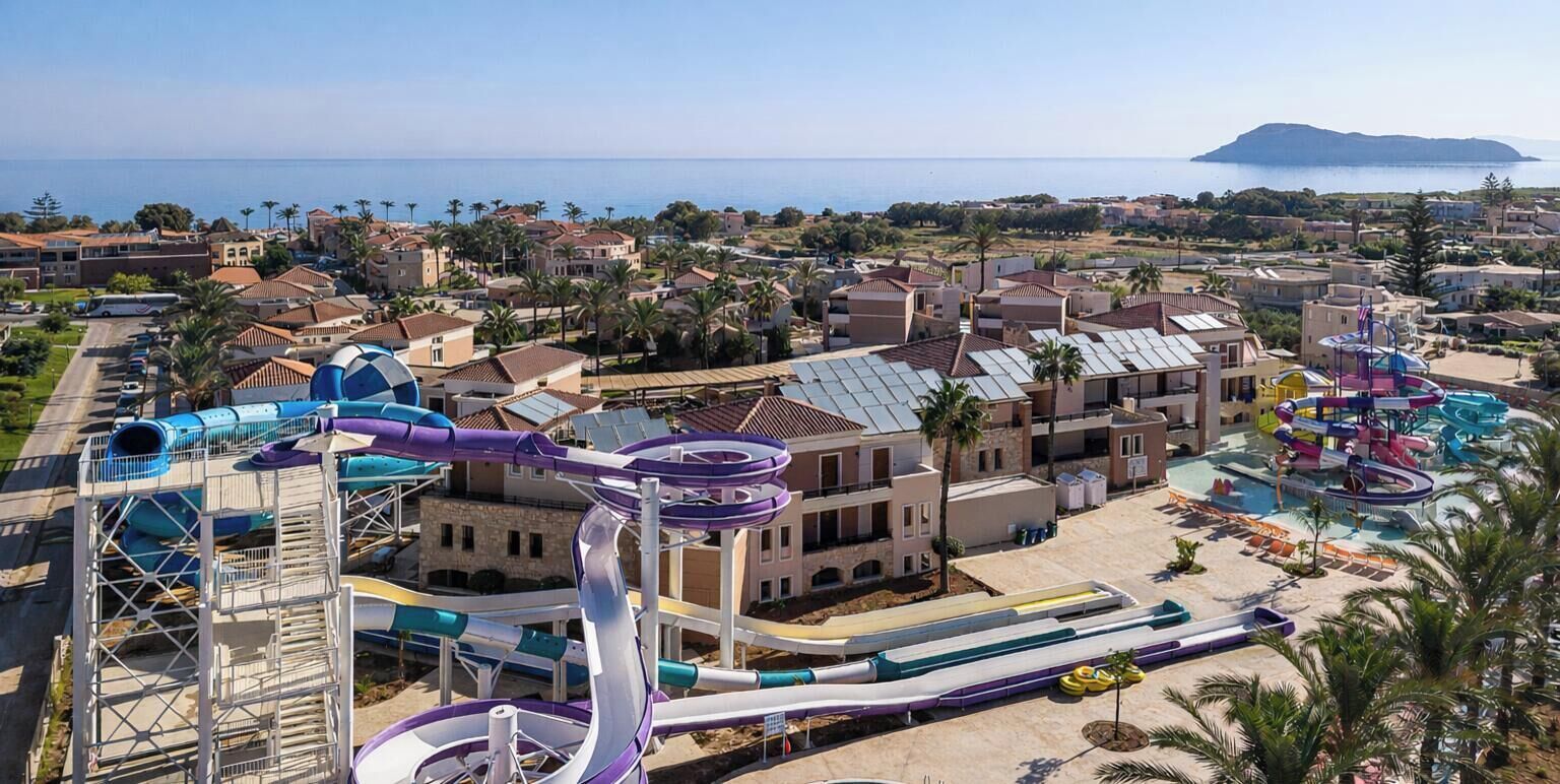 Resort med vandrutsjebaner, poolområde og udsigt over havet og en fjerndliggende ø.