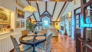 A dining area with a round table, wicker chairs, and a hanging light fixture. - Apartments Vrandecic (Postira)