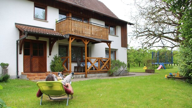A house with a balcony, a front door, and a small garden area.