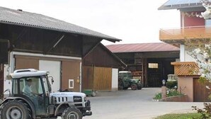 A building with a large garage door, a parked tractor, and a small vehicle in front.