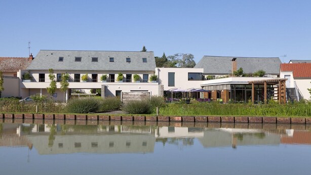 A modern building with a flat roof, large windows, and a reflection in the water. - Gite in the heart of the village (Belleville-sur-Loire)