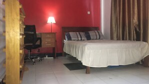 Une chambre à coucher comprenant un lit, un bureau, une chaise, une lampe et une armoire.