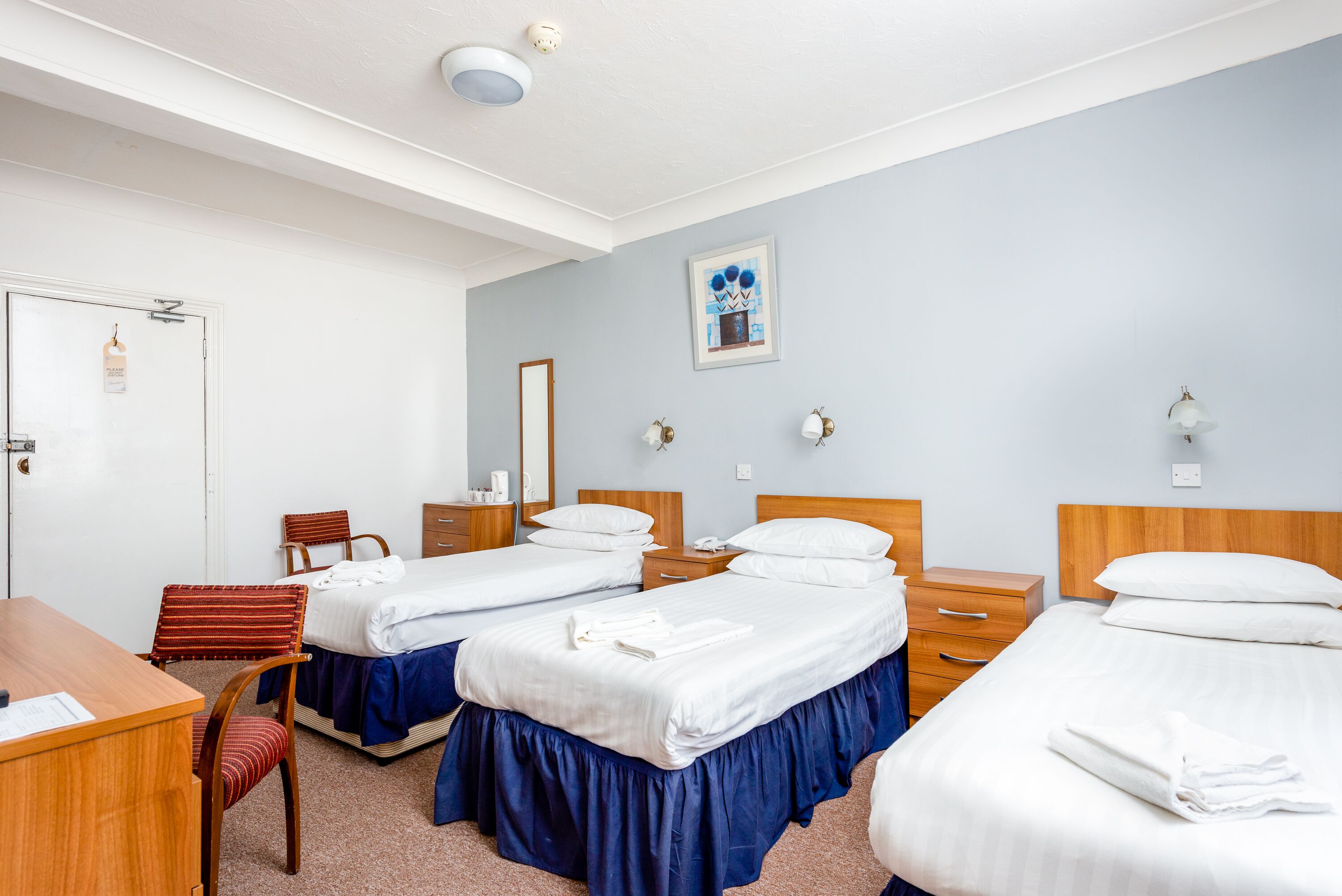 Ett hotellrum med två sängar, ett skrivbord och en stol.