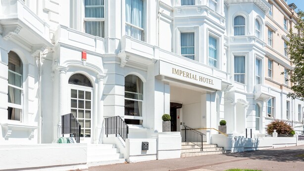 Un edificio blanco con el letrero "IMPERIAL HOTEL" en la entrada.