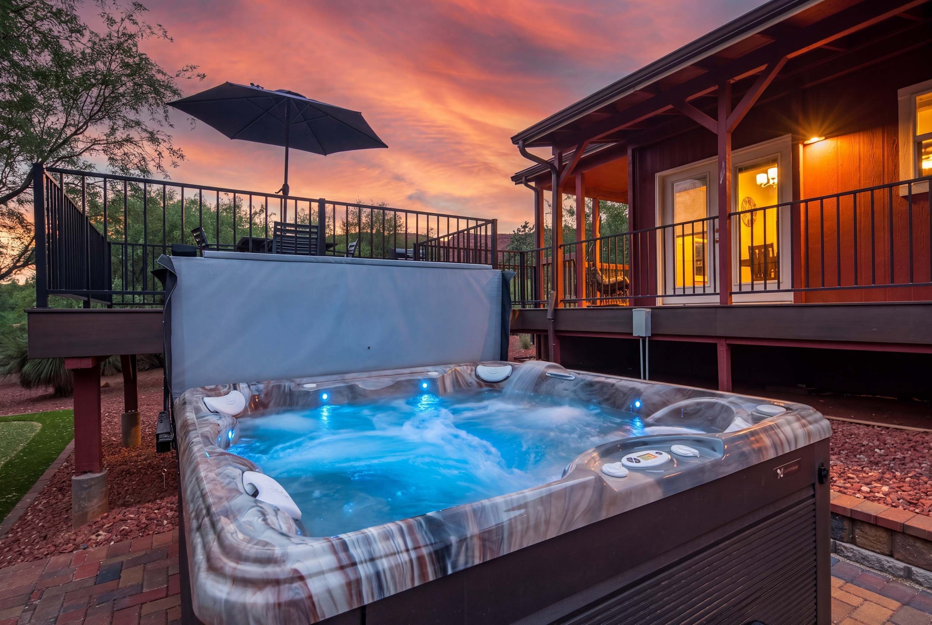 Un jacuzzi con caída de agua, una terraza techada con asientos exteriores y vistas al atardecer.
