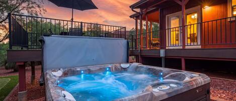 Un jacuzzi con caída de agua, una terraza techada con asientos exteriores y vistas al atardecer.