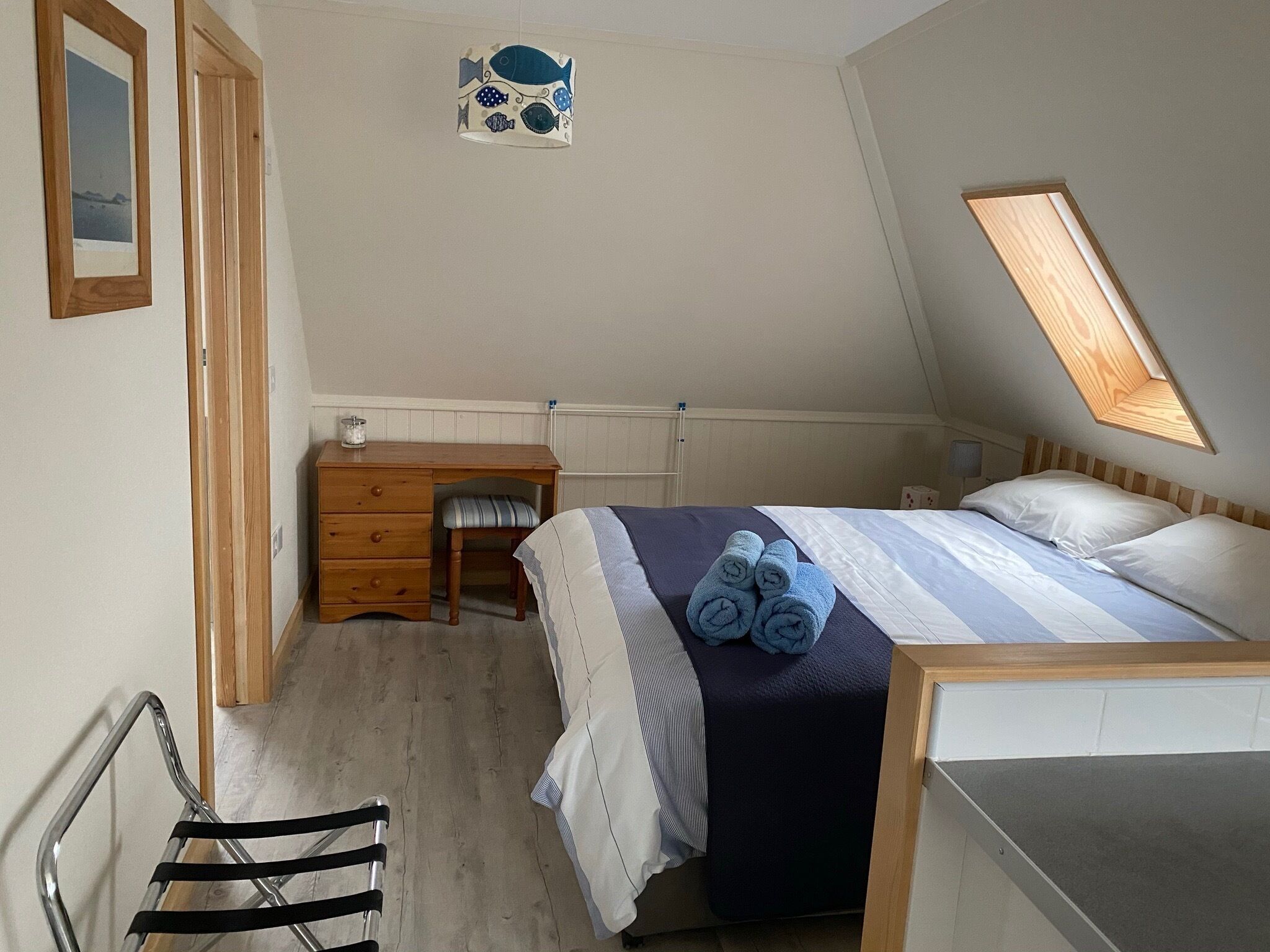 Un dormitorio con una cama, un escritorio, una silla y una ventana pequeña.