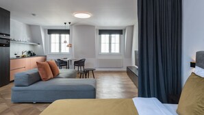 Et moderne hotelværelse med sofa, seng, spisebord og et tekøkken.