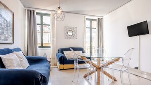 A modern living room with a glass dining table, two sofas, and a TV mounted on the wall. - Central apartment with parking to discover Granada (Granada)
