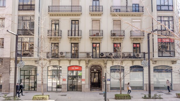 A multi-story building with a prominent entrance, large windows, and a red sign indicating a business. - Central apartment with parking to discover Granada (Granada)