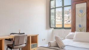 A bedroom with a bed, a desk, and a chair. There is a window with a view of buildings. - Central apartment with parking to discover Granada (Granada)