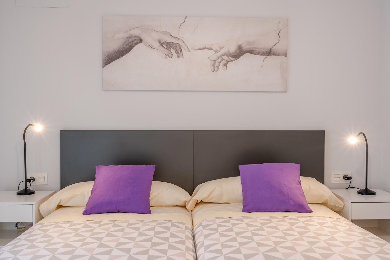 Ein Schlafzimmer mit einem großen Bett, zwei Nachttischen, zwei Lampen und einem Wandbild.
