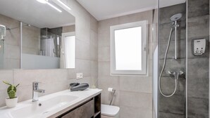 Een moderne badkamer met een groot wastafel, toilet en een douchecabine met glazen wanden.