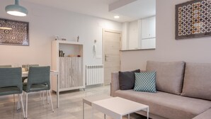Een moderne woonkamer met een bank, twee fauteuils, een salontafel en een eethoek met een tafel en stoelen.