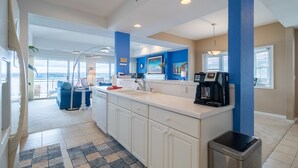 A modern kitchen with white cabinets, a black coffee maker, and a view to the outside.