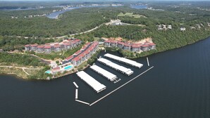 An aerial view of a waterfront resort with multiple buildings, a dock, and a swimming pool.