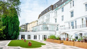 A courtyard with a lawn, potted plants, and a white building with the sign "Abbey Lawn Hotel".