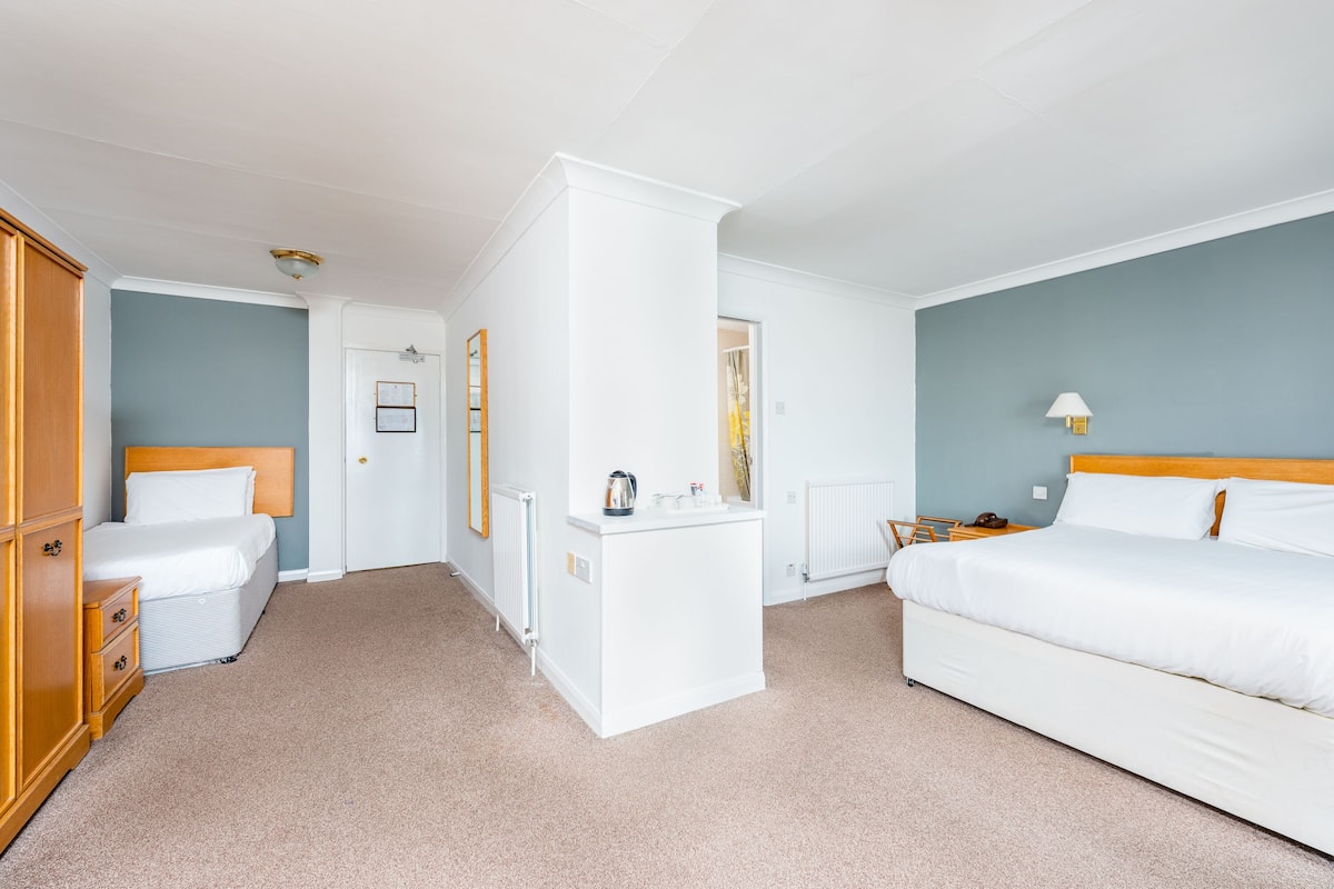 Ein Hotelzimmer mit Bett, Schminktisch, Schreibtisch und Heizkörper.