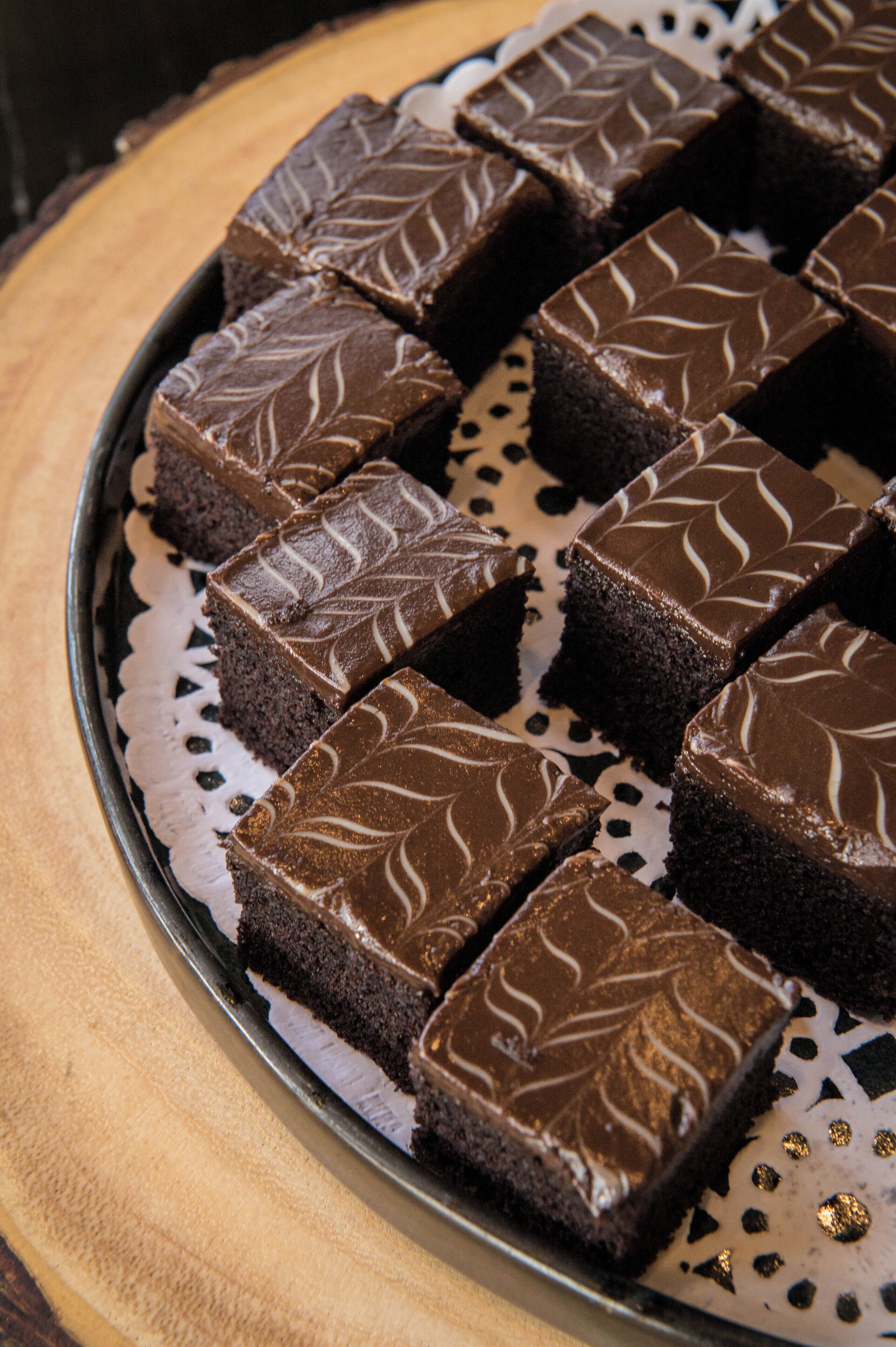 A tray of chocolate brownies with a decorative pattern on top, placed on a wooden table.