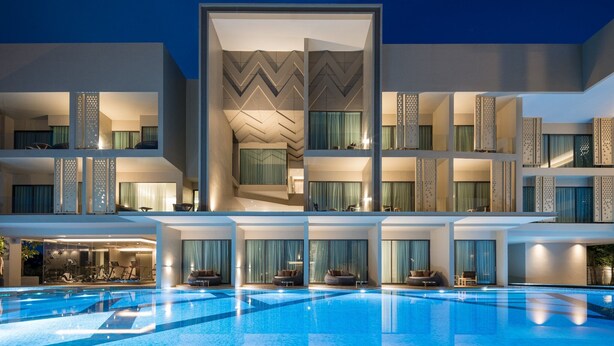Ein modernes Hotel mit Schwimmbad, mehreren Balkonen und einer geometrischen Fassade.