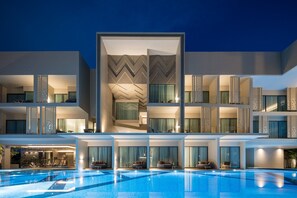 Een modern hotel met een zwembad, meerdere balkons en een geometrisch gevelontwerp.