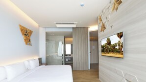 Ein modernes Hotelzimmer mit einem großen Bett, einem flachbildfernseher an der Wand und Holzboden.