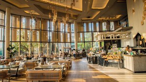 Ein geräumiges Restaurant mit hohen Decken, großen Fenstern und Holztischen und -stühlen.