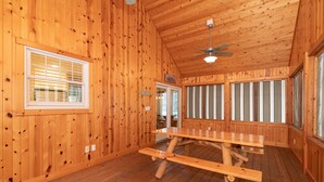 A wooden interior with a large table and ceiling fan.