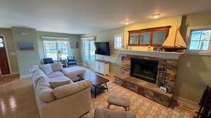 A living room with a sectional sofa, a fireplace, a television, and a sailboat decoration.