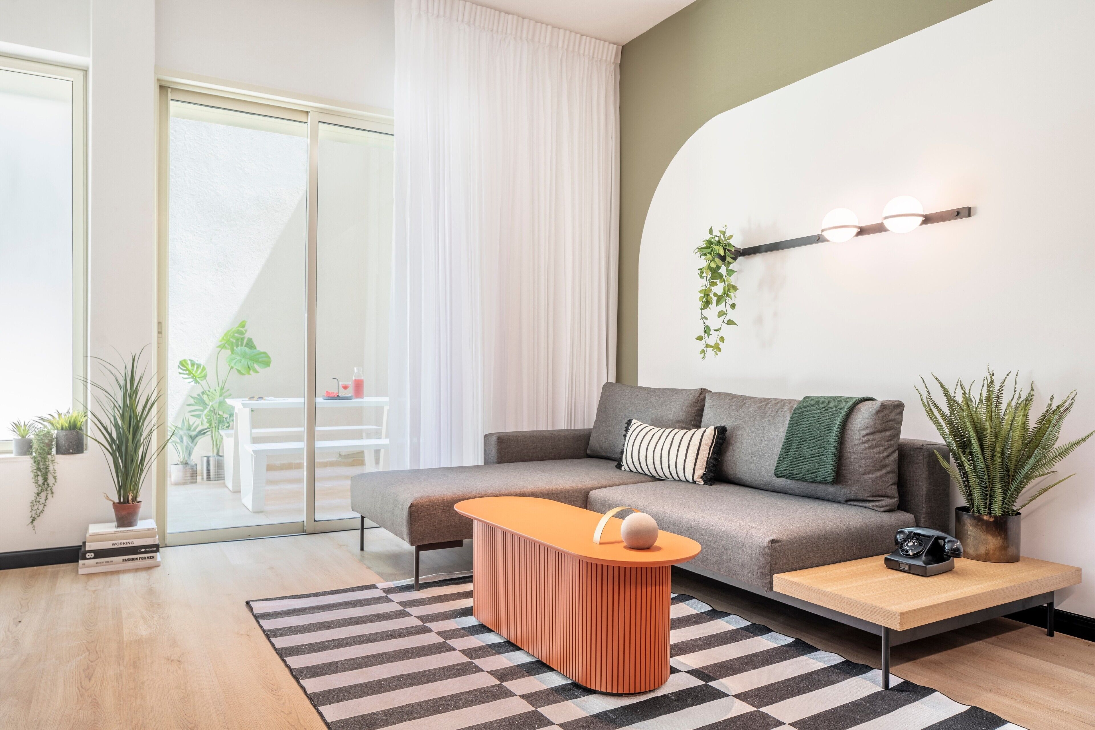 A modern living room with a sofa, a coffee table, a side table, and a potted plant.