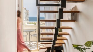 A modern interior with a wooden staircase, a glass door leading to a balcony, and a potted plant. - Mr. Montana - By TLV2GO (Tel Aviv)
