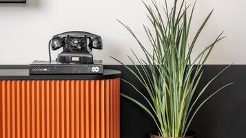 Una habitación moderna con un mueble negro y naranja, una planta en maceta y una pila de libros.