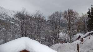 Eine verschneite Landschaft mit einer Holzhütte, die teilweise von Schnee bedeckt ist.