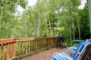 A wooden deck with a grill and striped lounge chairs. - Bike • Hike • Ski • Cozy and Affordable (Salida)
