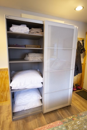 A wardrobe with multiple shelves, a hanging rod, and a door with a handle.