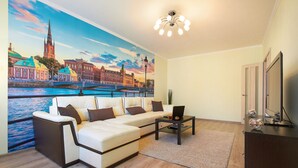 Olohuone, jossa on sohva, sohvapöytä ja TV-taso.