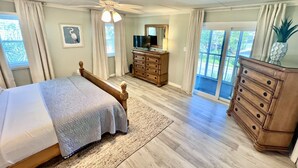 A bedroom with a bed, a dresser, a television, and a sliding glass door to the outside. - Marooned Mariner, Tybee Island (TYBEE ISLAND)