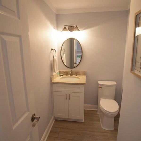 Et badeværelse med toilet, håndvask og spejl.