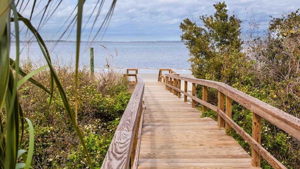 Una passerella in legno che conduce a una spiaggia con una vista libera sull'oceano.