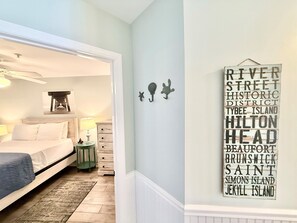 Ein Schlafzimmer mit Bett, Nachttisch, Lampe und einer Wand mit einem Schild, das verschiedene Orte auflistet.
