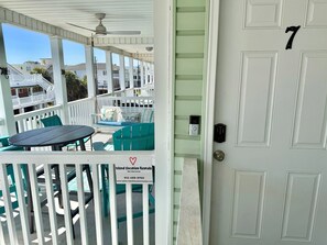 Eine Veranda mit Tisch und Stühlen, ein Schild für Island Vacation Rentals und eine Tür mit der Nummer 7.