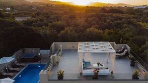 A rooftop terrace with a swimming pool, lounge chairs, and a glass-enclosed seating area with a view of the surrounding landscape. - Private pool villa with water massage pool and sea view roof garden (zakynthos)