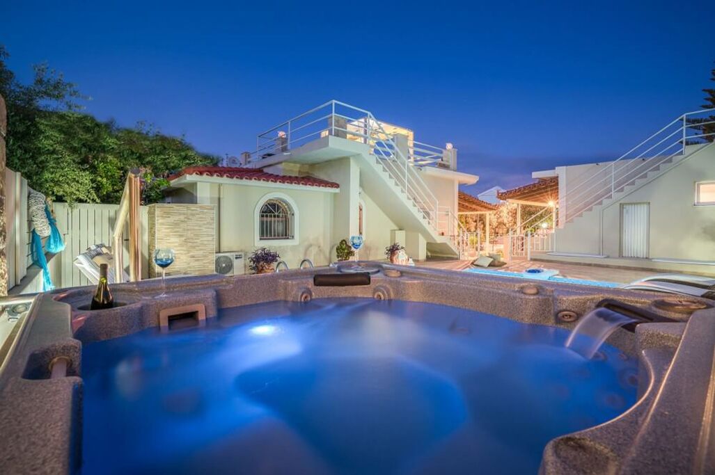 A hot tub area with a stone exterior, a staircase, and a pool.