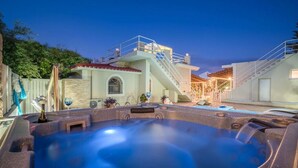 A hot tub area with a stone exterior, a staircase, and a pool. - Private pool villa with water massage pool and sea view roof garden (zakynthos)