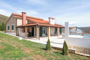 A modern house with a covered patio, a swimming pool, and a landscaped garden. - Villa Dea (Vučevica)